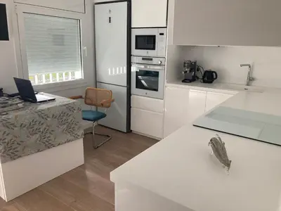 a kitchen with white cabinets and a laptop on a counter at APARTAMENTO 10 MIN SITGES in Puigmoltó