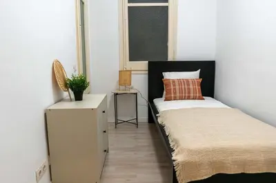 a small bedroom with a bed and a window at Orange crush Barcelona in Barcelona