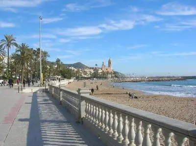 a beach with a fence and people on the beach at Apartamentospedroche Sitges in Sitges
