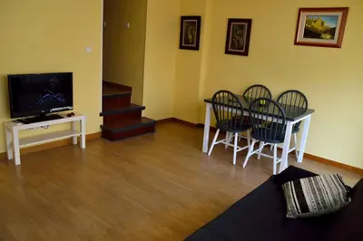 a living room with a table and chairs and a television at Apartamentospedroche Sitges in Sitges