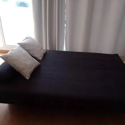 a black bed with a pillow and a window at Apartamentospedroche Sitges in Sitges