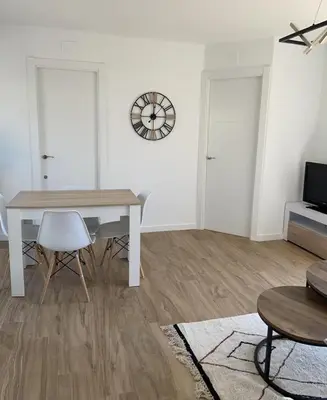 a living room with a table and chairs and a clock at Apartamento entre mar y montaña in Arenys de Munt