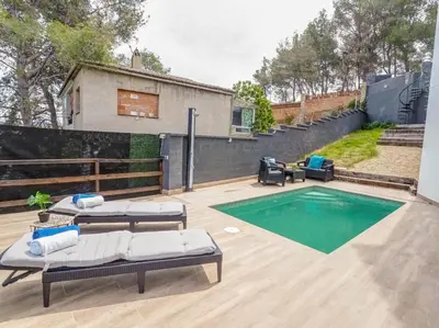 a swimming pool with two chaise lounges next to a house at Villa Papallona by Hello Homes Sitges in Sant Pere de Ribes