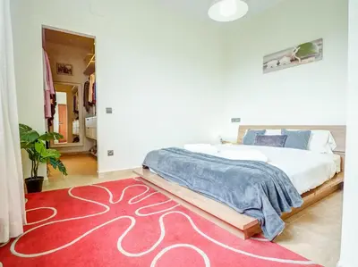 a bedroom with a large bed and a red rug at Villa Papallona by Hello Homes Sitges in Sant Pere de Ribes