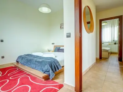 a bedroom with a bed and a red rug at Villa Papallona by Hello Homes Sitges in Sant Pere de Ribes