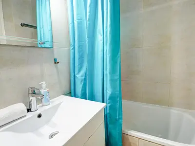 a bathroom with a sink and a blue shower curtain at Espalter Onyx by Hello Homes Sitges in Sitges