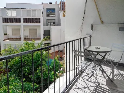 a balcony with a table and a chair and a building at Espalter Onyx by Hello Homes Sitges in Sitges