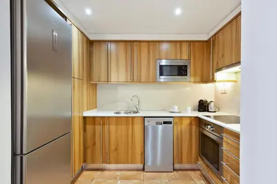 a kitchen with wooden cabinets and a stainless steel refrigerator at Columbus Apartment in Barcelona