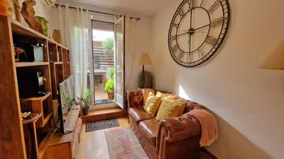 a living room with a couch and a clock on the wall at Àtic Trobador in Barcelona