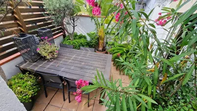 a wooden table and chairs in a garden with plants at Àtic Trobador in Barcelona