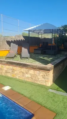 a couple of chairs sitting next to a swimming pool at Casa rustica con piscina y jardin in Pineda de Mar