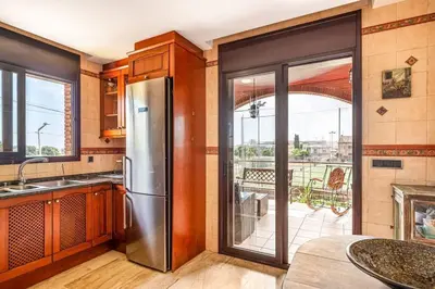 a kitchen with a stainless steel refrigerator and a balcony at Casa rustica con piscina y jardin in Pineda de Mar