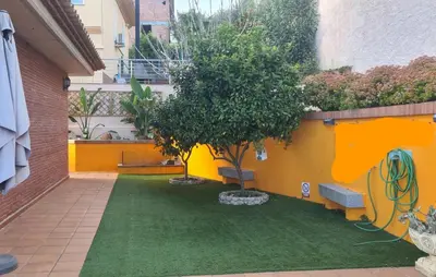 a courtyard with a tree and a yellow wall at Casa rustica con piscina y jardin in Pineda de Mar