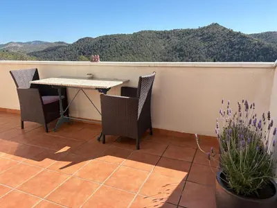 a table and chairs on a balcony with mountains in the background at Olivella Bed&breakfast in Olivella