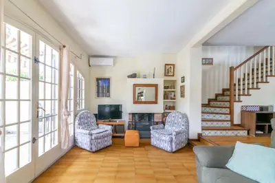 a living room with two chairs and a television at Paola: Preciosa casa pareada con piscina in Sitges
