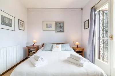 a bedroom with a white bed and a window at Paola: Preciosa casa pareada con piscina in Sitges