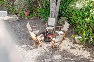 a group of chairs and a table with a tree at Paola: Preciosa casa pareada con piscina in Sitges
