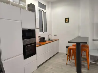 a kitchen with white cabinets and a black counter top at La casa del Mamut - Viladecans in Viladecáns