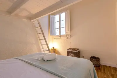 a bedroom with a bed with a white bedspread and a window at Aragó Suites in Barcelona