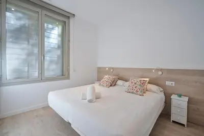 a bedroom with a large white bed and a window at BcnStop Sant Pau Suites in Barcelona