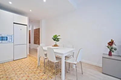 a white dining room with a white table and chairs at BcnStop Sant Pau Suites in Barcelona