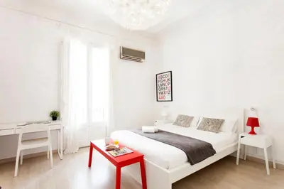 a white bedroom with a white bed and a red table at 1554 - AB Passeig de Gràcia Pelai in Barcelona