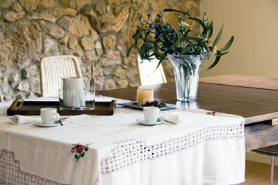 a table with a white table cloth and a vase of flowers at Ca l'Helena in Castellet