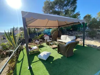 a gazebo with a bed and chairs under it at Le Petit Paradis Olivella in Olivella