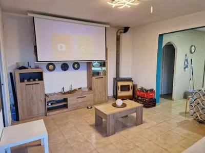 a living room with a large screen and a table at Le Petit Paradis Olivella in Olivella