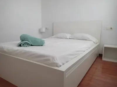 a white bed with a green pillow on it at Ap4Us B1 - Apartment for us - Sightseeing & Beach near to Barcelona in Badalona