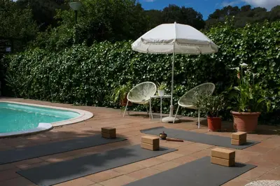 two chairs and an umbrella next to a swimming pool at Casa Magnolia in Dosríus
