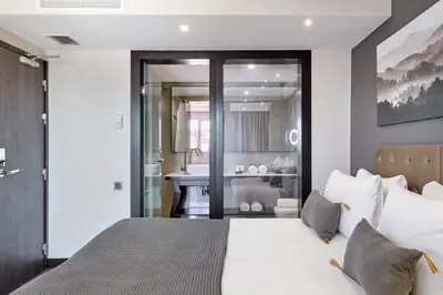 a bedroom with a large bed and a bathroom at Hotel Cortes Rambla in Barcelona