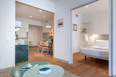 a bedroom with a bed and a room with a table at Aspasios City Oasis Apartments in Barcelona