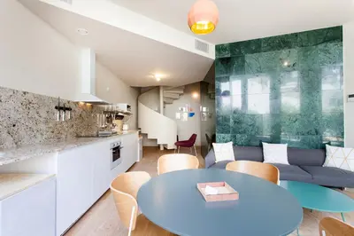 a kitchen and living room with a blue table and chairs at Aspasios City Oasis Apartments in Barcelona