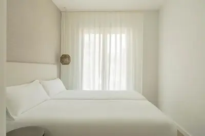 a white bed in a room with a window at Europa Apartments in Hospitalet de Llobregat