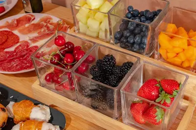 a wooden table topped with plastic containers filled with fruit at Antonios Hostal in Sitges