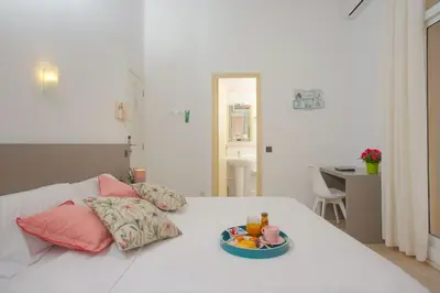 a white bed with a bowl of fruit on it at Antonios Hostal in Sitges
