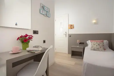 a bedroom with a desk and a bed and a table with flowers at Antonios Hostal in Sitges
