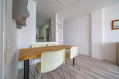 a dining room with a wooden table and white chairs at HomeHolidaysRentals Aquilone - Costa Barcelona in Pineda de Mar