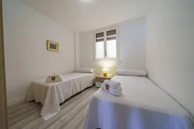 a white room with two beds and a window at HomeHolidaysRentals Aquilone - Costa Barcelona in Pineda de Mar