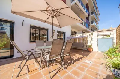 a patio with a table and chairs and an umbrella at HomeHolidaysRentals Fortuny - Costa Barcelona in Pineda de Mar
