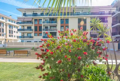 a bush with red flowers in front of a building at HomeHolidaysRentals Fortuny - Costa Barcelona in Pineda de Mar