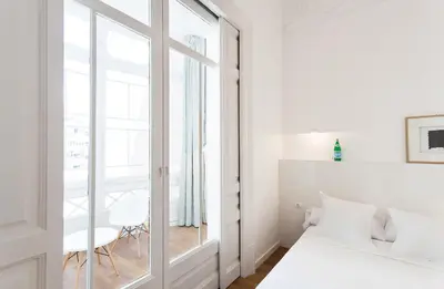 a white bedroom with a bed and a window at Hostal Argo in Barcelona