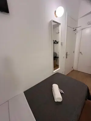 a white room with a bed with a towel on it at Hostal Argo in Barcelona