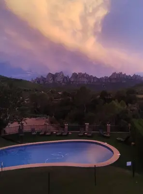 a swimming pool with chairs and mountains in the background at Cal Poldo in Marganell