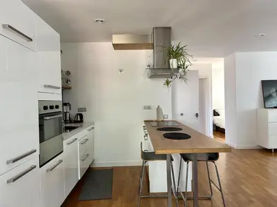a kitchen with white cabinets and a wooden table at Loft Bouquet Alella mar y montaña 25 min a BCN in Alella