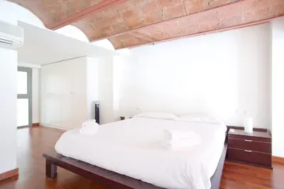 a white bedroom with a large bed with white sheets at LetsGo Paseo de Gracia in Barcelona
