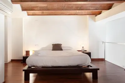 a bedroom with a bed with white sheets and wooden ceilings at LetsGo Paseo de Gracia in Barcelona