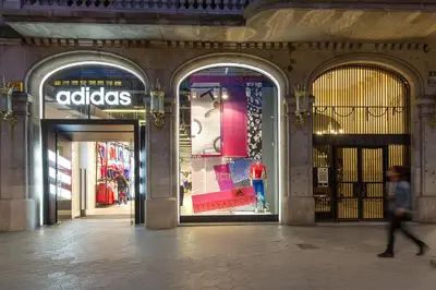 a person walking in front of an adidas store at LetsGo Paseo de Gracia in Barcelona