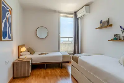 two beds in a room with a window at AB Olympic Village III Penthouse in Barcelona